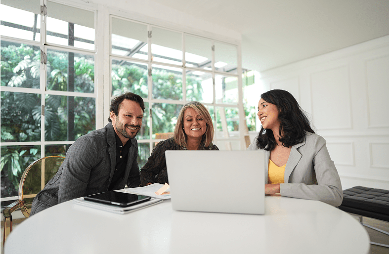 Three people smiling at a laptop.