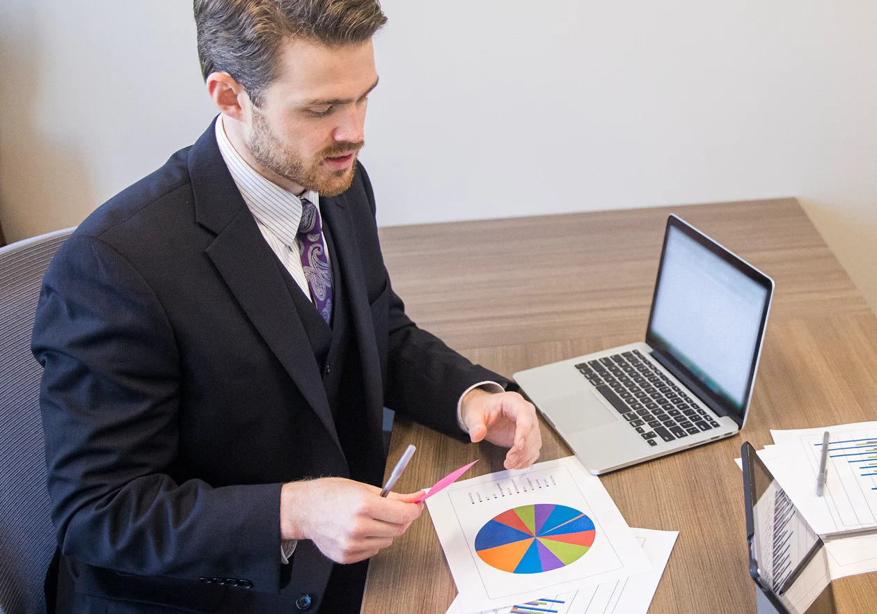 Man analyzing charts at office desk.