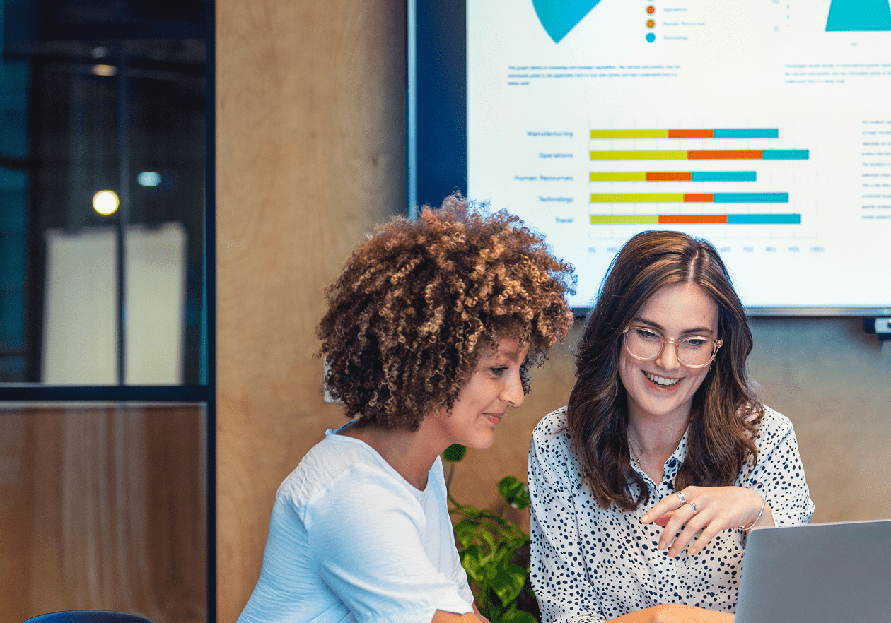 Two women discussing data on a laptop.